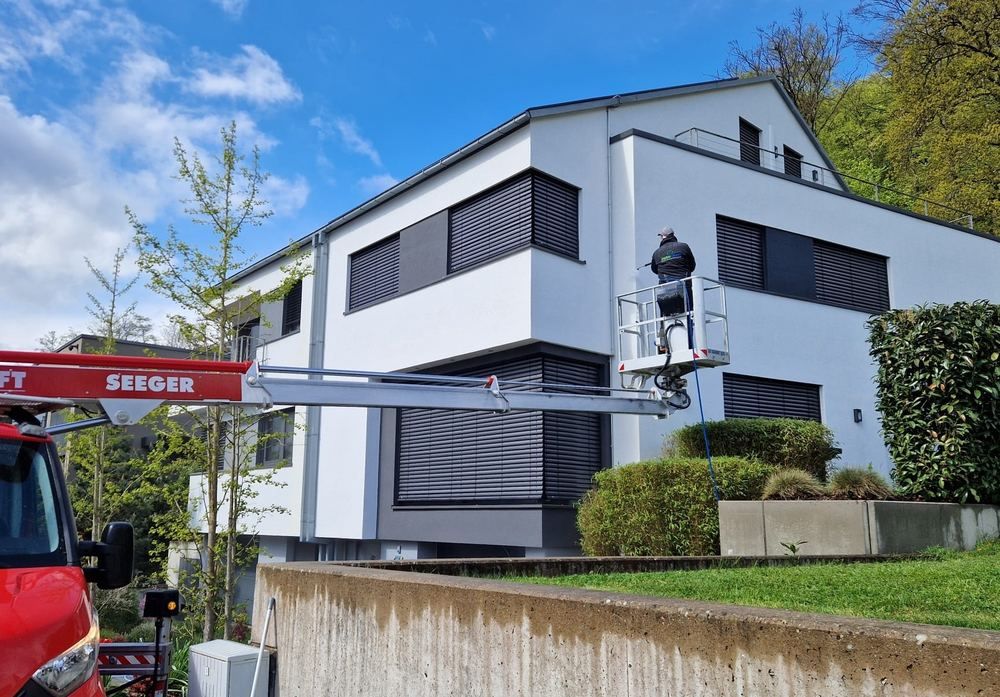 instaclean-Mitarbeiter reinigt mit Teleskoplanze von einer Arbeitsbühne aus eine Hausfassade